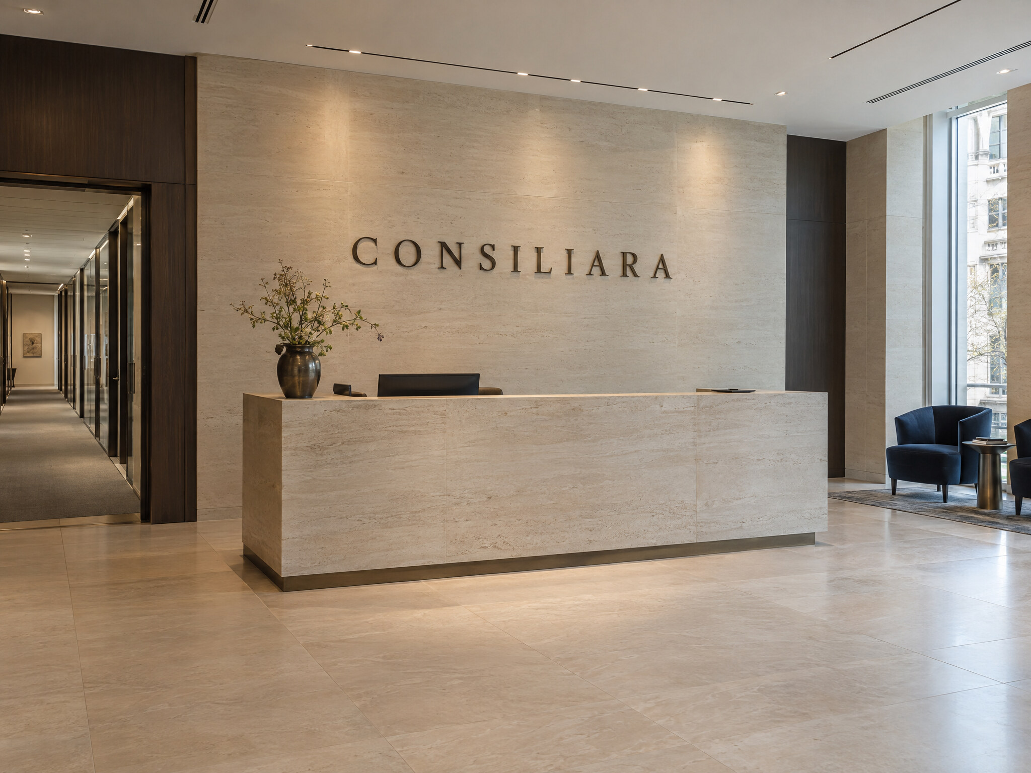 Contemporary reception with a pale stone desk and CONSILIARA wordmark on the wall